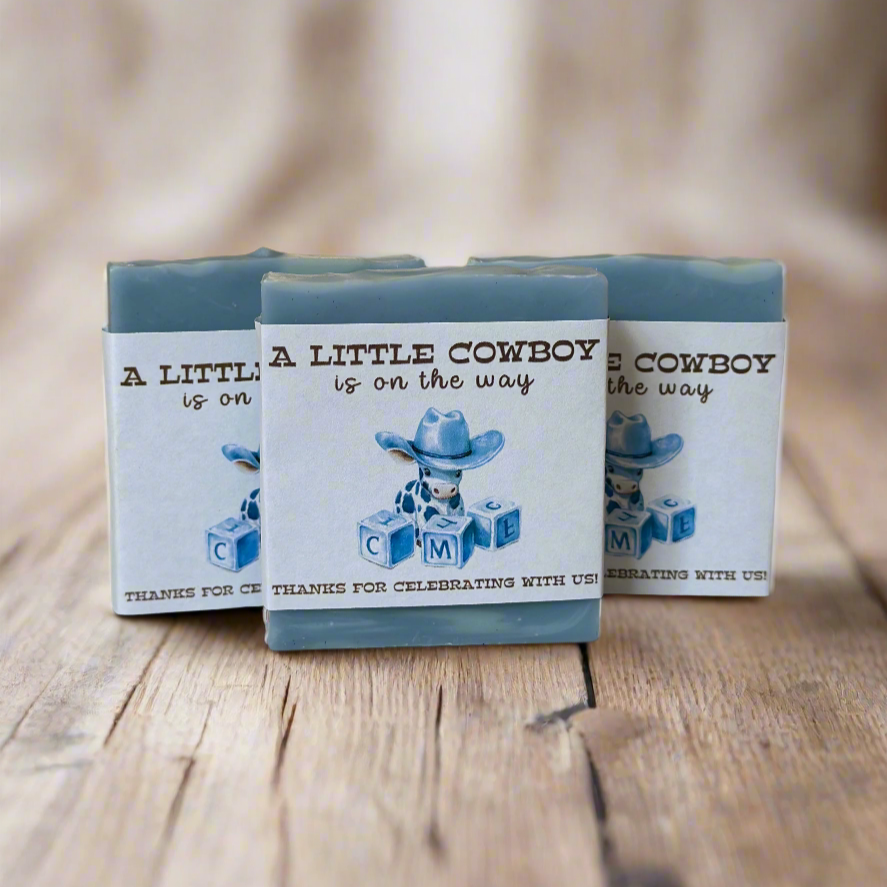Three blue small soap favors with cowboy-themed design on a wooden surface