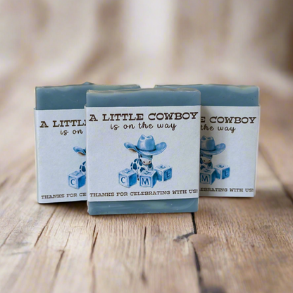 Three blue small soap favors with cowboy-themed design on a wooden surface
